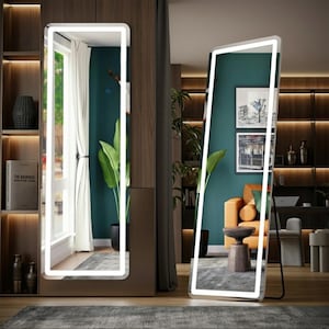 Puede incluir: Dos espejos de cuerpo entero con iluminación LED blanca brillante. Un espejo está en posición vertical, el otro está apoyado en un soporte negro. Los espejos están en una habitación con una ventana, plantas y una zona de estar.