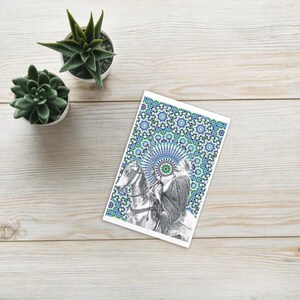 Peut inclure: Carte de vœux avec une illustration en noir et blanc d'une personne à cheval, sur fond de motifs géométriques bleus et verts. Deux petites plantes succulentes en pot sont également visibles.