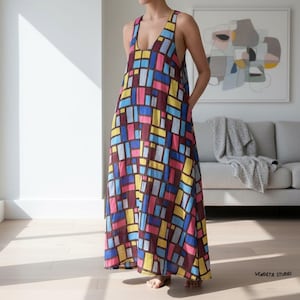 May include: A sleeveless, floor-length dress with a V-neckline. The dress features a colorful geometric pattern of rectangles in shades of burgundy, pink, blue, yellow, and gray. The dress is made of a lightweight fabric and is suitable for warm weather.