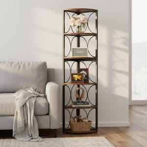 May include: A tall, corner bookshelf with five shelves. The shelves are made of wood and supported by a black metal frame. The shelves are decorated with a vase of flowers, a speaker, framed photos, headphones, books, and a basket.
