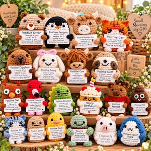 May include: A collection of small, handmade crochet plush animals and figures, each holding a white sign with a positive message. The set includes an otter, penguin, highland cow, cat, capybara, bunny, cow, sloth, owl, flamingo, dinosaur, cupcake, reindeer, poop, cat, potato, duck, turtle, pig, and shark.