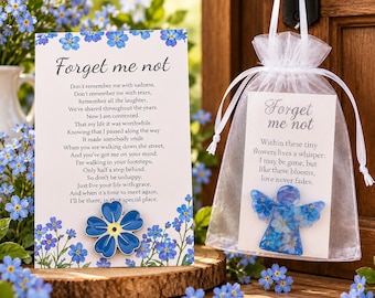 May include: A white card with blue forget-me-not flowers and a poem titled Forget me not, featuring a blue flower pin. Beside it, a white organza bag contains a card with an angel-shaped resin ornament filled with blue forget-me-not flowers.