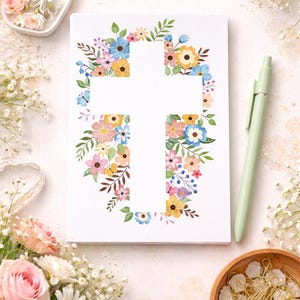 May include: A white card with a cross-shaped cutout, surrounded by colorful watercolor flowers and green leaves. A light green pen, flowers, and decorative items are arranged around the card, creating a floral theme.
