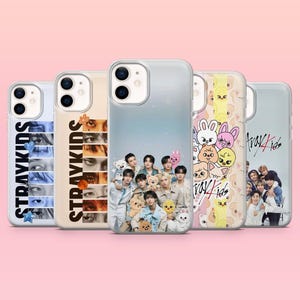 Könnte beinhalten: Fünf Handyhüllen mit verschiedenen Designs werden gezeigt. Die Hüllen zeigen Bilder einer Musikgruppe, Zeichentrickfiguren und Nahaufnahmen von Augen. Der Text "Stray Kids" ist auf einigen Hüllen aufgedruckt. Die Hüllen sind transparent und haben eine glänzende Oberfläche.