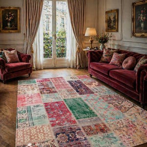 Könnte beinhalten: Ein Patchwork-Teppich mit verschiedenen rechteckigen Farbfeldern in Rot-, Grün- und Blautönen. Der Raum umfasst auch ein rotes Sofa, Sessel und ein Fenster mit Vorhängen. Der Teppich verleiht dem Raum eine gemütliche Atmosphäre.