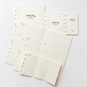 May include: A collection of cream-colored planner inserts in three sizes, each featuring the text Month Plan and Semper Co. Ltd. The pages include punched holes for binding, grid layouts, and monthly calendar grids with headers for days of the week.