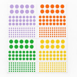 May include: A collection of adhesive sticker sheets featuring rows of circular dots in various sizes and colors, including lavender, orange, green, and yellow. The stickers are arranged in organized grids on white rectangular backing paper sheets.