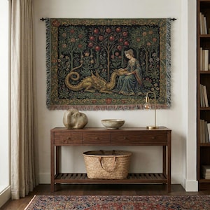 Könnte beinhalten: Ein rechteckiger, gewebter Wandteppich mit dunklem Hintergrund, der eine zentrale Figur in einem blauen Gewand zeigt, die inmitten von Granatapfelbäumen mit einem goldenen Drachen interagiert. Der Teppich hat eine dekorative Bordüre und Fransen.