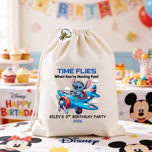 May include: A cream-colored drawstring bag featuring a cartoon image of Stitch piloting a blue airplane. The text "TIME FLIES When You're Having Fun!" and "RILEY'S 3RD BIRTHDAY PARTY 2026" are printed on the bag. A bumble bee sticker is on the top.