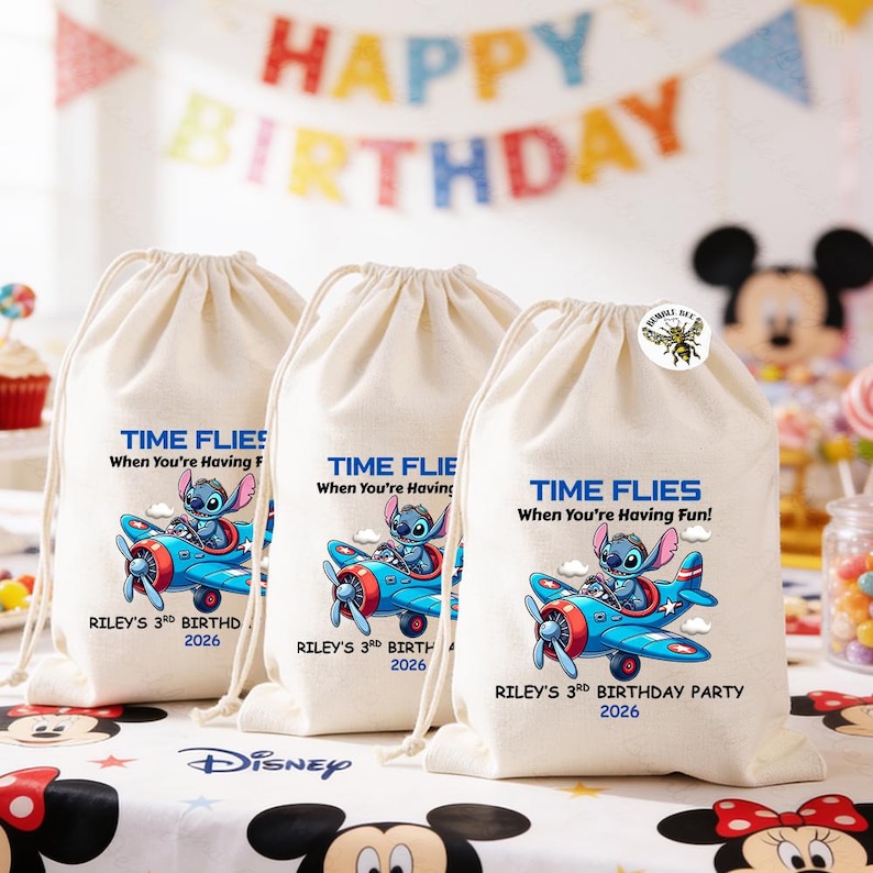 May include: Three off-white drawstring bags with a blue airplane graphic featuring a cartoon character. Text on the bags reads "TIME FLIES When You're Having Fun!" and "RILEY'S 3rd BIRTHDAY PARTY 2026". A "HAPPY BIRTHDAY" banner is in the background.