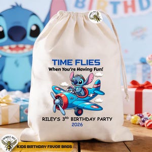 May include: A cream-colored drawstring bag featuring a blue cartoon character piloting a blue airplane. Text on the bag reads "TIME FLIES When You're Having Fun!" and "RILEY'S 3RD BIRTHDAY PARTY 2026". The bag is labeled "KIDS BIRTHDAY FAVOR BAGS".