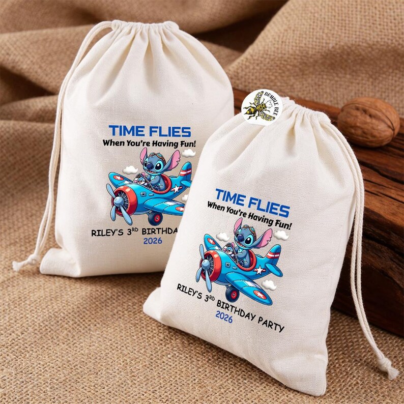 May include: Two off-white drawstring bags with a blue and red airplane graphic featuring a cartoon character. Text on the bags reads "TIME FLIES When You're Having Fun!" and "RILEY'S 3RD BIRTHDAY PARTY 2026".