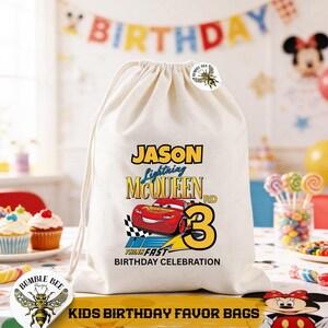 Puede incluir: Una bolsa con cord&oacute;n de color crema con un dise&ntilde;o de Lightning McQueen, el nombre "JASON" y el n&uacute;mero "3". La bolsa incluye el texto "THINK FAST BIRTHDAY CELEBRATION" y "KIDS BIRTHDAY FAVOR BAGS". Tambi&eacute;n es visible un logotipo de Bumble Bee.