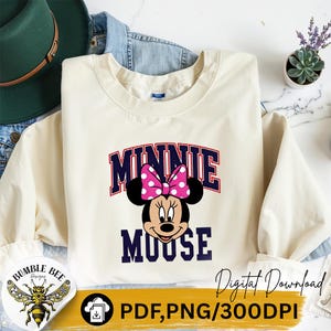 May include: Cream-colored sweatshirt featuring a graphic of Minnie Mouse with a pink polka-dot bow. The word "MINNIE" is arched above the character, and "MOOSE" is below. The design is in navy blue and red. The words "Digital Download" are also visible.