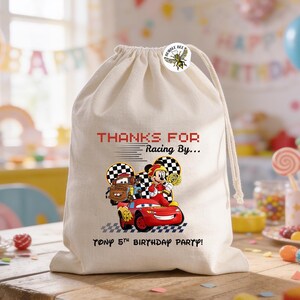 K&ouml;nnte beinhalten: Beige Kordelzugbeutel mit einem bunten Cartoon-Autodesign und dem Text "THANKS FOR Racing By... TONY 5TH BIRTHDAY PARTY!". Der Beutel hat einen "BUMBLE BEE" Aufkleber.