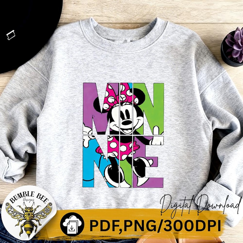 May include: A light gray sweatshirt featuring a colorful graphic of Minnie Mouse. The word "MINNIE" is spelled out in large, block letters with Minnie Mouse's image incorporated into the design. The design includes the text "PDF, PNG/300DPI".