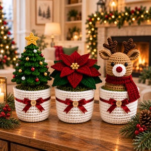 May include: Three crocheted Christmas decorations in white pots with red ribbons and wooden buttons. The set includes a green Christmas tree with a yellow star and ornaments, a red poinsettia plant, and a brown reindeer wearing a red scarf.