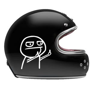 Op de afbeelding: Een glanzend zwarte motorhelm met een witte lijntekening-sticker van een stokfiguur met een norse uitdrukking die zijn middelvinger opsteekt. De helm heeft een zilverkleurige rand rond de gezichtsopening en vier kleine ronde ventilatieopeningen.
