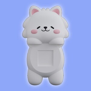 May include: A white, cartoon-style animal figurine with a rounded head, pointed ears with pink inner details, and pink circular cheeks. The figure has a small black nose and mouth, with a square-shaped cutout centered on its smooth, solid body.