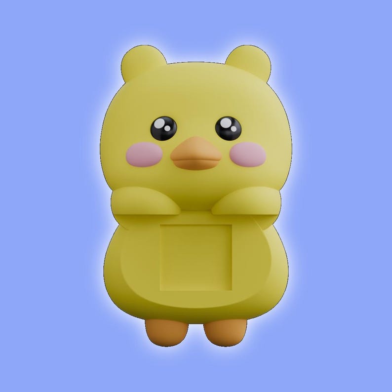 May include: A yellow cartoon character figurine with rounded ears, large black eyes, a small orange beak, and pink circular cheeks. The figure has a square indentation on its torso and two small orange feet at the base, presented against a blue background.
