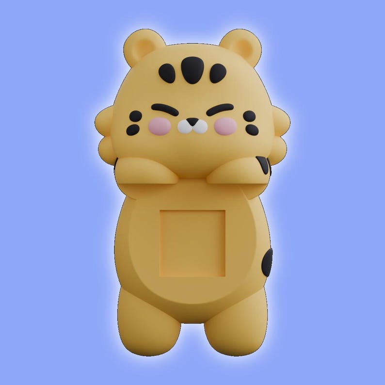 May include: A yellow tiger-shaped phone stand with a smooth matte finish. The character features black spots on the forehead and cheeks, pink circular cheeks, and a small white nose. A square cutout is centered on the torso for device support.