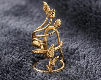 May include: A gold-coloured ring with an intricate floral design. The ring features delicate leaves and buds, with a wrap-around style. The ring's design includes a series of leaves and buds, creating a nature-inspired aesthetic.