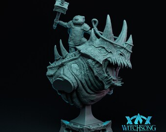 May include: A teal-colored resin miniature bust featuring a frog-like humanoid warrior in armor holding a hammer, mounted atop a large, horned, reptilian creature with an open mouth. The base includes the text WITCHSONG in a stylized font.
