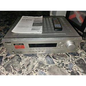 Può includere: Un ricevitore audio Onkyo HT-R8230 color argento dotato di display digitale, una grande manopola del volume e vari pulsanti di controllo. L'unità include un telecomando e un manuale di istruzioni etichettato HT-R8230, con adesivo 600 watt.