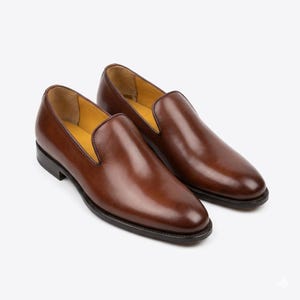 Handmade mens plain wholecut Venetian loafer in warm tan brown full grain leather on white background