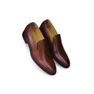 Men's tan brown wholecut loafer photographed on marble steps showing slim streamlined silhouette
