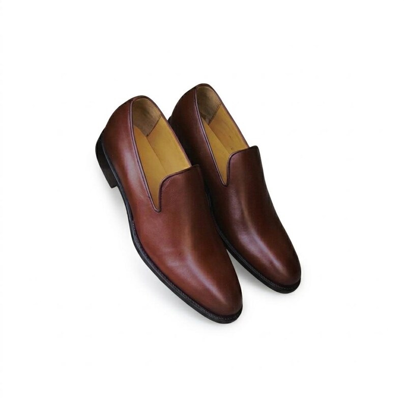 Men's tan brown wholecut loafer photographed on marble steps showing slim streamlined silhouette