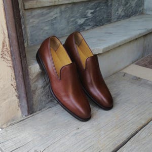 Pair of mens smooth calf leather slip on loafers with V-shaped vamp opening and dark topline piping
