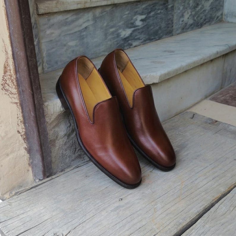 Pair of mens smooth calf leather slip on loafers with V-shaped vamp opening and dark topline piping