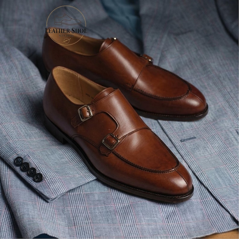 Handmade brown double monk strap leather shoes side view on grey background