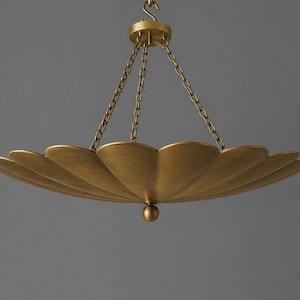 May include: A gold-colored, scalloped-edge chandelier with a central sphere. The light fixture is suspended by chains from a circular ceiling mount. The design is reminiscent of a stylized flower or shell.