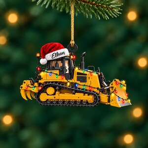 Gepersonaliseerd geel acryl kerstornament in de vorm van een bulldozer, cadeau met eigen naam voor een machinist van zwaar materieel.