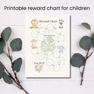 Op de afbeelding: Een afdrukbare beloningskaart voor kinderen met de tekst "Reward Chart", "You can do it!" en "You dit it!". De kaart bevat illustraties van een leeuw, giraffe, zebra, olifant en aap. De achtergrond is wit met een groen bladerenpatroon.