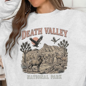 May include: A white ceramic mug with a black handle and the text "But First, Coffee" in a black, handwritten-style font. The mug is on a white surface.