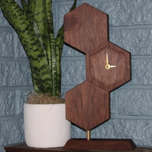 May include: A set of three ceramic mugs with a speckled, matte finish. The mugs are in shades of cream, light gray, and dark gray. Each mug has a simple, minimalist design and a rounded handle.