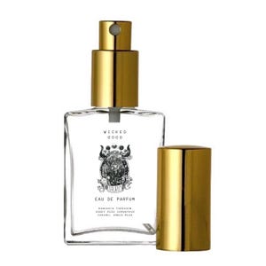 May include: A clear glass perfume bottle with a gold-colored cap and sprayer. The bottle has a label with the words "WICKED GOOD" and "TAURUS" along with an illustration of a bull. The scent notes are listed below the illustration.