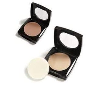 May include: Two open compacts with mirrors, one with a beige powder and the other with a light brown powder. A round, white powder puff sits next to one of the compacts. The compacts have black cases.