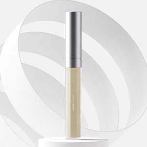 May include: A silver-capped, cylindrical cosmetic tube with a clear body filled with a shimmering, light beige liquid. The text "COME OF NATURE" is printed vertically on the tube. The product is displayed on a white pedestal against a backdrop of white ribbons.