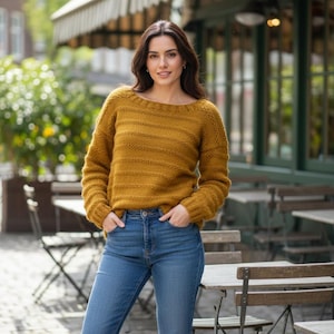 May include: Mustard yellow knit sweater with a boat neck and horizontal ribbed design. The long-sleeved sweater is paired with blue jeans. The image is taken outdoors, with a blurred background of a cafe.