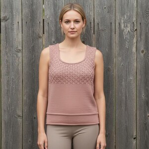 May include: A sleeveless, rose-colored top with a square neckline and a textured diamond pattern on the upper chest. The bottom half of the top is a solid color, with a horizontal band at the waist. The model is wearing beige pants.