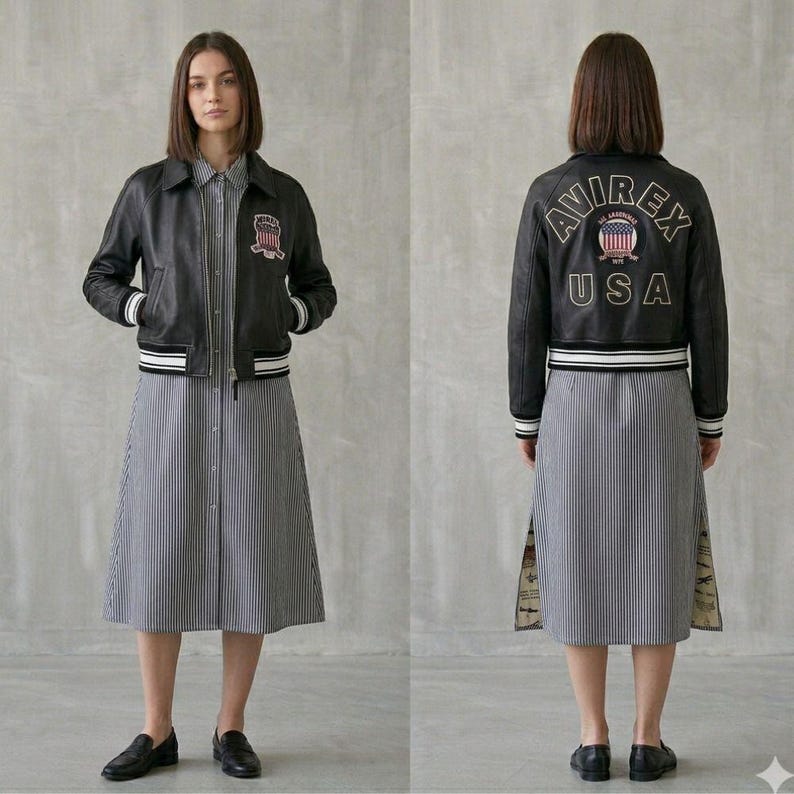 Puede incluir: Chaqueta de cuero negra con ribete a rayas blancas y negras y parche a juego. La chaqueta se lleva sobre un vestido a rayas. La parte trasera de la chaqueta tiene el texto "AVIREX USA" con un emblema patri&oacute;tico.