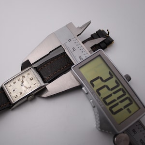 Digital caliper measuring the lug-to-lug length of the PRONTO watch at 38.04mm, with the watch on a brown leather strap.
