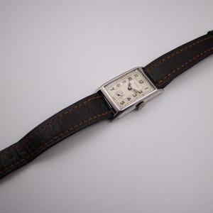 Top-down view of the PRONTO watch laid flat, displaying the brown leather strap and overall length.