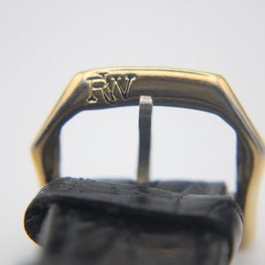 Close-up of the gold-tone buckle, clearly displaying the engraved 'RW' logo.