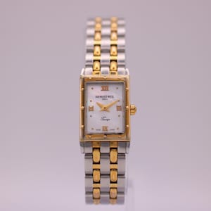 May include: A rectangular Raymond Weil Tango wristwatch featuring a white mother-of-pearl dial with gold-tone Roman numeral markers and hands. The watch has a two-tone stainless steel and gold-plated link bracelet with a matching rectangular case.