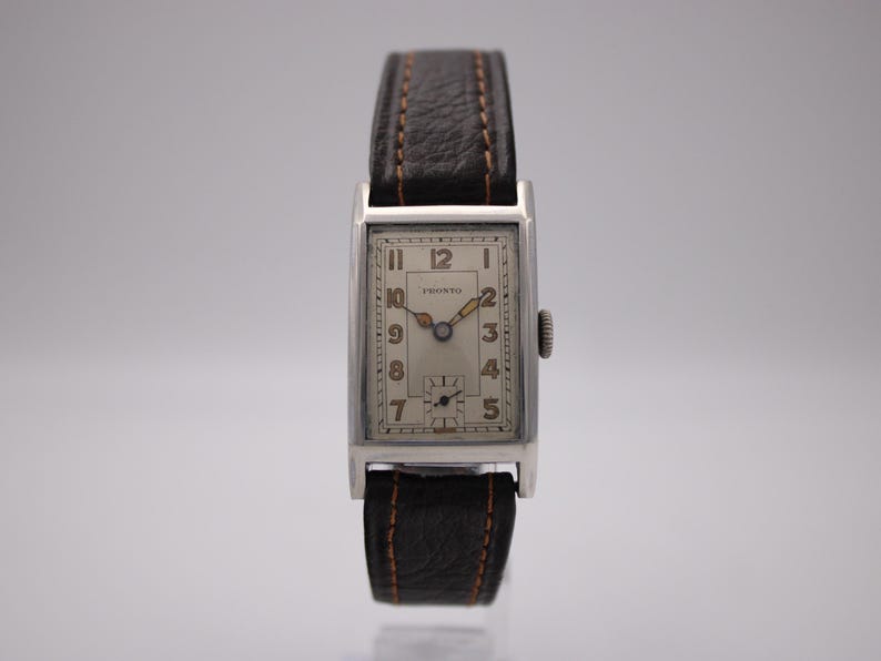 Front view of the vintage PRONTO watch with cream dial and brown leather strap on a stand.